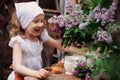 Kid girl at garden tea party in spring day with bouquet of lilacs syringa