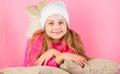 Kid girl knitted hat. Winter accessory concept. Girl long hair dream pink background. Kid dreamy lean on pillows. Winter Royalty Free Stock Photo