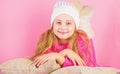 Kid girl knitted hat. Winter accessory concept. Girl long hair dream pink background. Kid dreamy lean on pillows. Winter Royalty Free Stock Photo