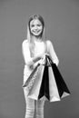 Kid girl with long hair fond of shopping. Girl on smiling face carries bunches of shopping bags, isolated on white Royalty Free Stock Photo