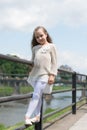 Kid girl with long hair walks near riverside, river on background. Girl child tourist enjoy sightseeing while walks Royalty Free Stock Photo