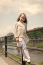 Kid girl with long hair walks near riverside, river on background. Girl child tourist enjoy sightseeing while walks Royalty Free Stock Photo