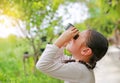 Kid girl kid looking ahead with binoculars in nature fields. Explore and adventure concept