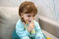 Kid girl makes inhalation with a nebulizer. sick child holding inhalator in hand and breathes through an inhaler at home