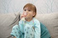 Kid girl makes inhalation with a nebulizer. sick child holding inhalator in hand and breathes through an inhaler at home