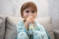 Kid girl makes inhalation with a nebulizer. sick child holding inhalator in hand and breathes through an inhaler at home