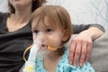 Kid girl makes inhalation with a nebulizer. sick child with mother holding inhalator in hand and breathes through an inhaler at