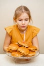 a kid girl makes a wish and blows out a candle on a hamburger cake.