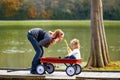 Kid girl and mother playing in lake with pull cart