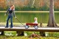 Kid girl and mother walking in lake with pull cart