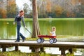 Kid girl and mother walking in lake with pull cart