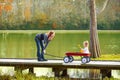 Kid girl and mother walking in lake with pull cart