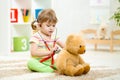 Kid girl playing doctor with plush toy at home Royalty Free Stock Photo