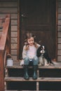 Kid girl playing with her spaniel dog, sitting on stairs at wooden log cabin Royalty Free Stock Photo