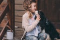 Kid girl playing with her spaniel dog, sitting on stairs at wooden log cabin Royalty Free Stock Photo