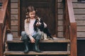 Kid girl playing with her spaniel dog, sitting on stairs at wooden log cabin