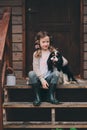 Kid girl playing with her spaniel dog, sitting on stairs at wooden log cabin Royalty Free Stock Photo