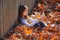 Kid girl playing tablet pc in autumn leaves Royalty Free Stock Photo