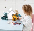Kid girl plays educational game interestedly with wooden colorful toy t-shirt with buttons and laces Royalty Free Stock Photo