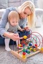 Kid girl plays with educational toy indoor. Happy mother looking at her smart daughter Royalty Free Stock Photo