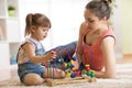 Kid girl plays with educational toy indoor. Happy mother teaching her smart daughter Royalty Free Stock Photo