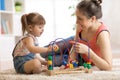 Kid girl plays with educational toy in nursery at home. Happy mother looking at her smart daughter. Royalty Free Stock Photo