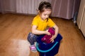 Kid girl with a ponytail in a yellow T-shirt and black leggings with stars washes the floor, squeezes a rag over a bucket. house Royalty Free Stock Photo