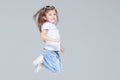 Kid girl preschooler in blue jeans, white t-shirt and sunglasses is jumping isolated on grey background Royalty Free Stock Photo