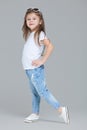 Kid girl preschooler in blue jeans, white t-shirt and sunglasses is posing isolated on grey background Royalty Free Stock Photo