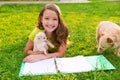 Kid girl and puppy dog at homework lying in lawn Royalty Free Stock Photo