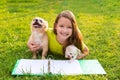 Kid girl and puppy dog at homework lying in lawn Royalty Free Stock Photo