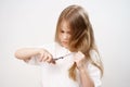 kid girl shears her long hair with scissors and afraid on a white background. Royalty Free Stock Photo