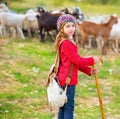 Kid girl shepherdess happy with flock of sheep and stick