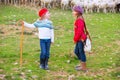 Kid girl shepherdess sisters happy with flock of sheep and stick