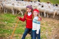 Kid girl shepherdess sisters happy with flock of sheep and stick