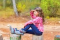 Kid girl sitting in forest trunk looking far away