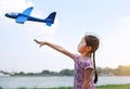 Kid girl throwing a toy plane to flying on air in the nature garden. Side view