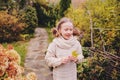 Kid girl walking in the garden in late october or november and playing with maple leaf. Children exploring nature