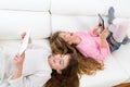 Kid girls having fun playing with tablet pc lying sofa