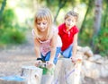 Kid girls playing on trunks in forest nature