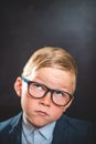 Kid in glasses with eyes looking up on blackboard. Funny thinking child boy.