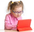 Kid in glasses looking at mini tablet pc screen at table