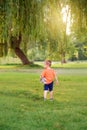 Kid going to future. Little cute toddler Caucasian boy in red orange t-shirt with stuffed plush toy walking alone in park. Royalty Free Stock Photo