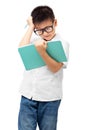Kid with hand on head and holding book, thinking, doing homework, learning difficulties, wearing eyeglasses Royalty Free Stock Photo