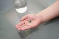 Kid hand hold pill supplement antioxidant vitamin mineral capsule with water glass before take medicine capsule for health care Royalty Free Stock Photo
