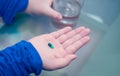 Kid hand hold pill supplement antioxidant vitamin mineral capsule with water glass before take medicine capsule for health care Royalty Free Stock Photo