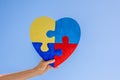 Kid hand holding colorful jigsaw puzzle heart over blue sky background. World autism awareness day, Autism spectrum Royalty Free Stock Photo