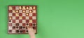 Kid hand moving chess figure, playing chess game. Chessboard on light green background, top view Royalty Free Stock Photo