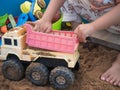 Kid hand playing car truck toy on sand background. Royalty Free Stock Photo
