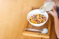 kid hand pouring fresh milk on the white cup, cornflakes cereal, strawberry, blackberry and milk in a white bowl, selective focus. Royalty Free Stock Photo